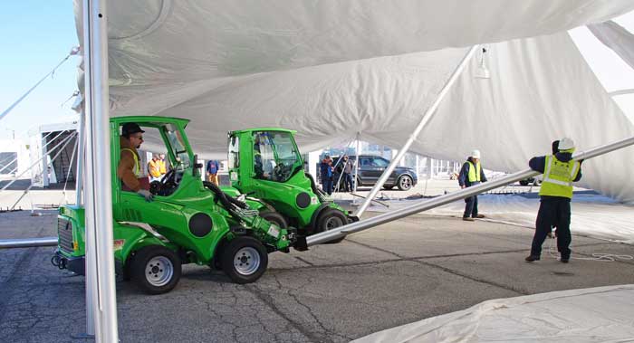 two Tent OX Machines equipped with OX Push Pockets raise center poles on an large Anchor Industries tent